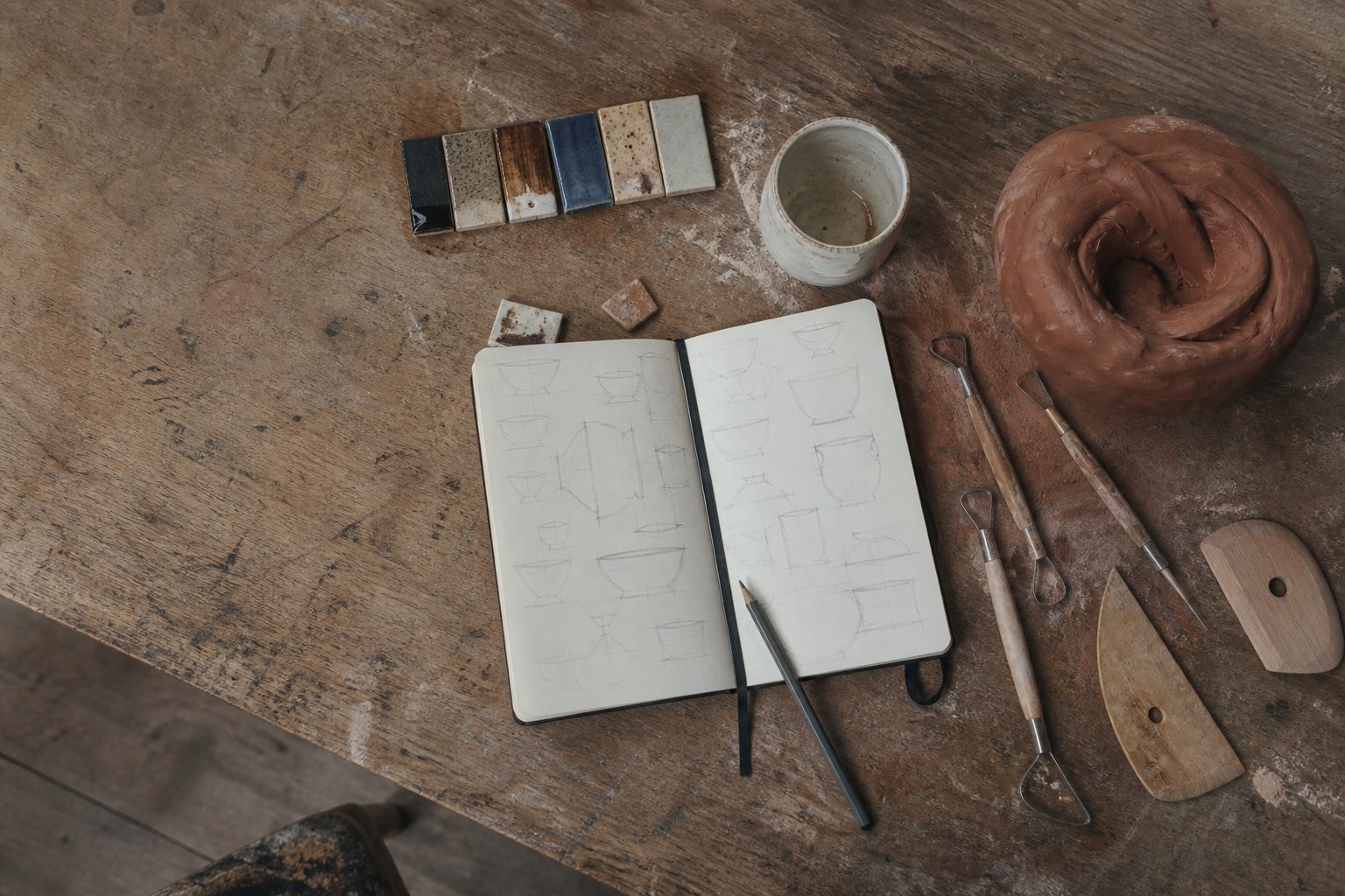 Carnet, outils et essais d’émaux sur une table de potier